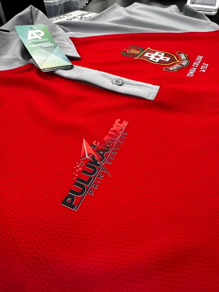 Red polo printed with the Pulukamu name and a crest, close up